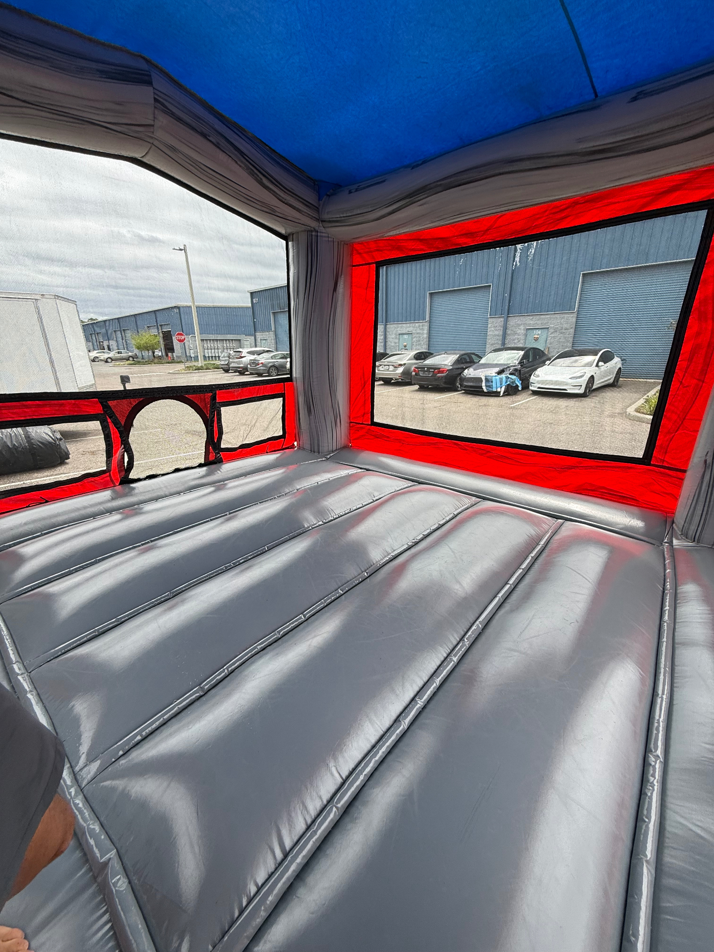 Inside of a grey and red bounce house after cleaning, with clear mesh windows and a spotless jumping surface.