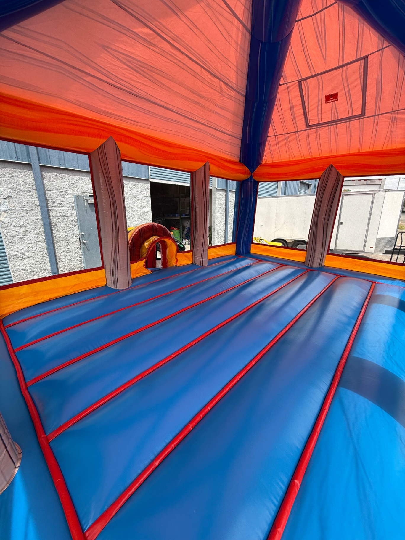 Inside view of a freshly cleaned orange and blue bounce house with spotless floor and walls.
